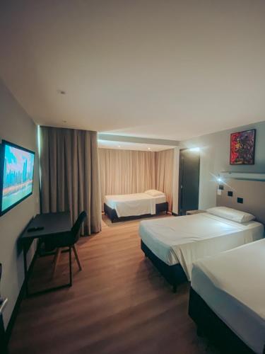 a hotel room with two beds and a desk at Dublê Hotel - The Original in Recife