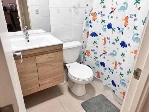 a bathroom with a toilet and a sink and a shower curtain at Comoda Estadia en Talcahuano in Talcahuano