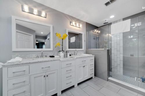 a white bathroom with two sinks and a shower at Palm Harbor Estate w/ Pool & Fruit Trees on Acre in Palm Harbor