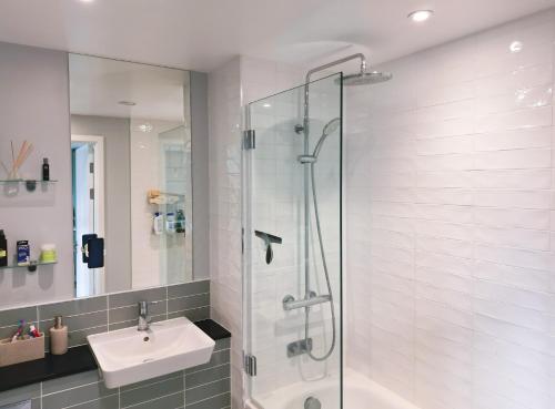 a bathroom with a glass shower and a sink at Luxe Apartment: 3 mins Luton Airport & Free Wi-Fi in Luton