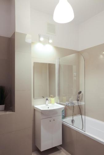 een witte badkamer met een wastafel en een bad bij ClickTheFlat Three Crosses Square Apart Rooms in Warschau