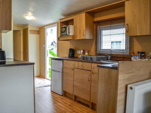 a kitchen with wooden cabinets and a counter top at Middlemuir Retreat in Tarbolton