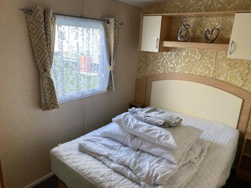 a bedroom with a bed with white sheets and a window at 2 and 3 Bedroom caravans with Hot Tubs at tattershall in Tattershall