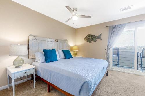a bedroom with a bed with blue pillows and a window at The Southern Harmony in Folly Beach