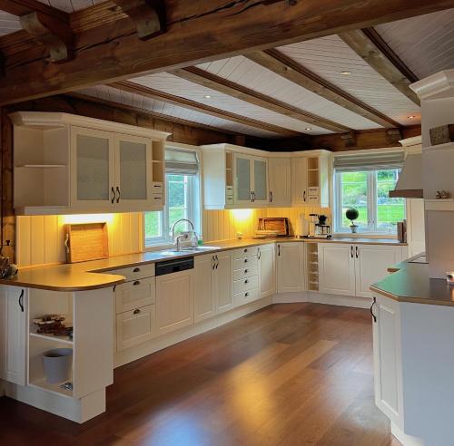 Il comprend une cuisine avec des placards blancs et un plafond en bois. dans l'établissement "SoFly Lodge", Charm and Elegance, à Noresund