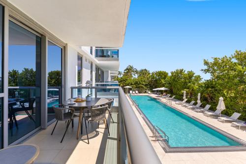 a balcony with a table and chairs and a swimming pool at Dharma Home Suites Miami Beach at Monte Carlo in Miami Beach