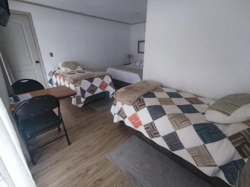a room with two beds and a table and a desk at Casa Hotel Trocha Angosta in Constitución