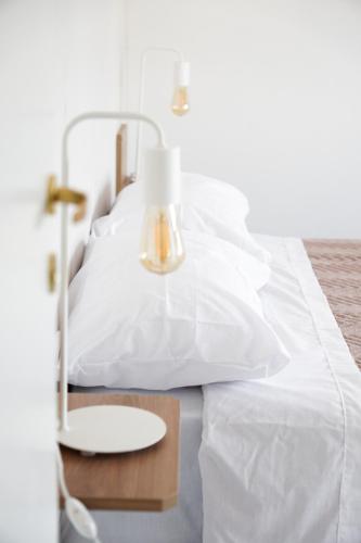 een bed met witte lakens en een tafel met een lamp bij HomeRental SF (departamentos céntricos en alquiler temporario) in Santa Fe