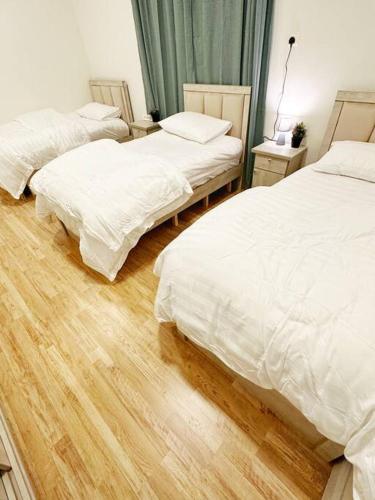 a bedroom with two beds and a wooden floor at شقة جميلة بغرفتين نوم ومدخل خاص 2BB in Riyadh