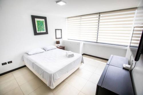 a white bedroom with a bed and a window at 1206 Increible suite en Puerto santa Ana in Guayaquil
