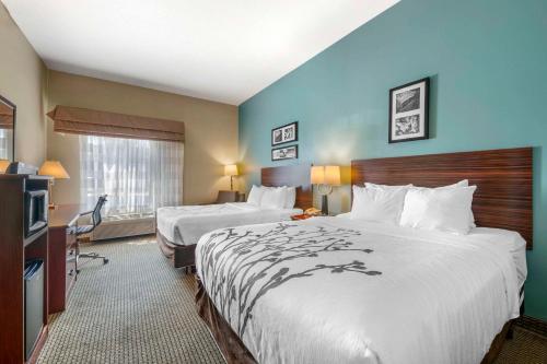 una camera d'albergo con due letti e una televisione di Sleep Inn & Suites a Rapid City