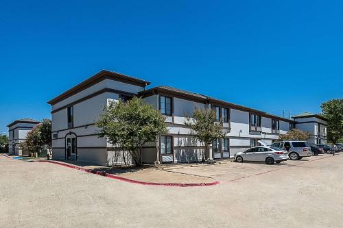 a large building with cars parked in a parking lot at Quality Inn & Suites Irving DFW Airport South in Irving