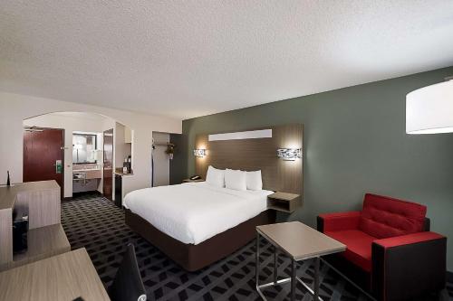 a hotel room with a bed and a red chair at Quality Inn & Suites DFW Airport South in Irving