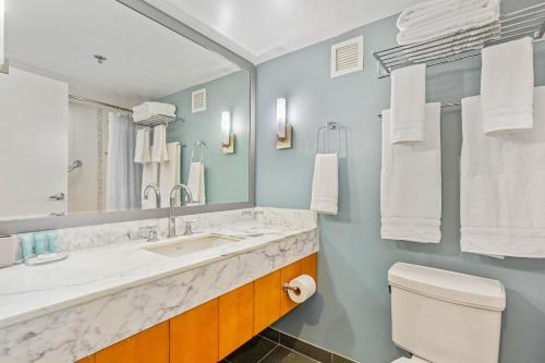 CASTLE at Ala Moana Hotel في هونولولو: حمام مع حوض ومرحاض ومرآة
