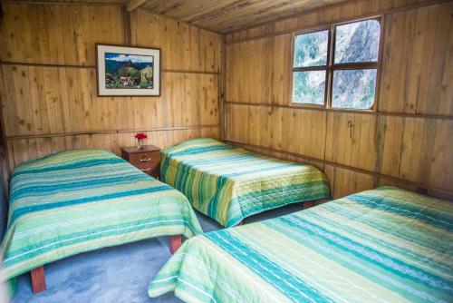 a room with two beds in a wooden cabin at Llahuar Lodge in Cabanaconde