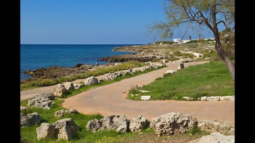 a dirt road next to the ocean with rocks at Stanze villa Morosini in Torre San Giovanni Ugento