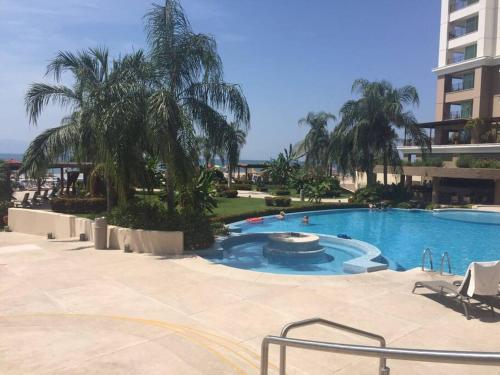 una grande piscina con palme e un edificio di Frente al mar Grand Venetian Puerto Vallarta a Puerto Vallarta