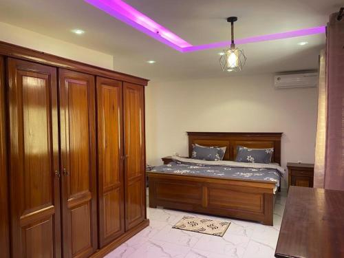 - une chambre avec un lit doté d'un mobilier en bois et d'une lumière violette dans l'établissement Villa OMARI Situé à Saly Portudal Villa 2 Chambres bien équipés proche de tout, à Saly Portudal