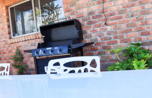 a barbecue grill sitting next to a brick wall at Kennedy Drive Boutique Motel - Close To City Centre & Airport in Tweed Heads