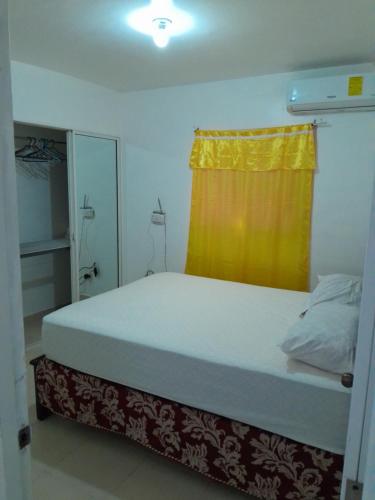 a small bedroom with a bed with a yellow curtain at Comodo apartamento en el centro de la ciudad in Santiago de los Caballeros