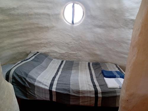 a bedroom with a bed in a cave with a window at Casa Ecológica Madre Tierra in Curití