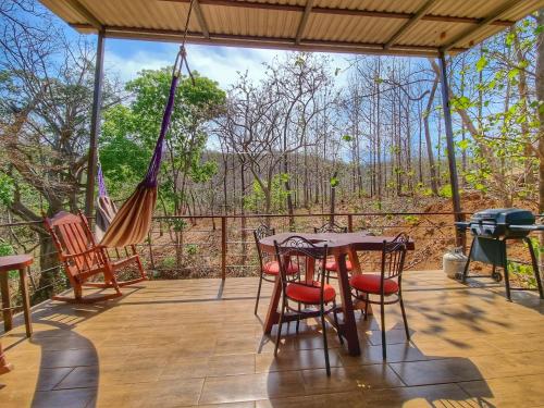 a porch with a table and chairs and a hammock at Pinilla Highlands Incredible mountain views in Tamarindo