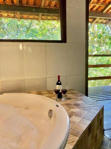 a bath tub with a bottle of wine and two glasses at Pousada Bella Ana in Visconde De Maua