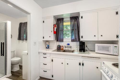 a white kitchen with white cabinets and a microwave at Cute as a Clam Cottage Room 5 in Ocean Park