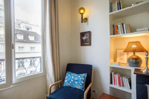 une chaise bleue dans une chambre avec fenêtre dans l'établissement Centrally located duplex Notre Dame, à Paris