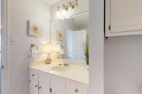 een witte badkamer met een wastafel en een spiegel bij Sand Castle 7A in Dauphin Island