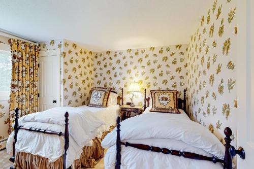 Duas camas num quarto com papel de parede floral em Village Green Unit 14E em Stowe