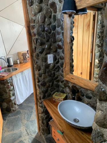 a bathroom with a sink and a stone wall at Nomade Patagonia Glamping & Domos in Trevelin