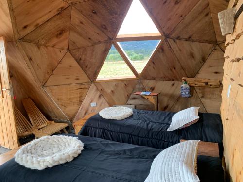 two beds in a wooden room with a window at Nomade Patagonia Glamping & Domos in Trevelin