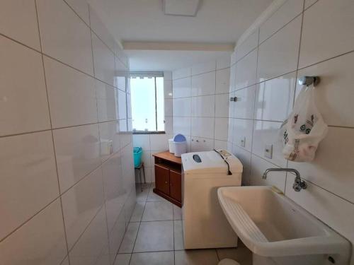 uma casa de banho branca com um lavatório e um WC em Apartamento pé na areia e piscina em Capão da Canoa