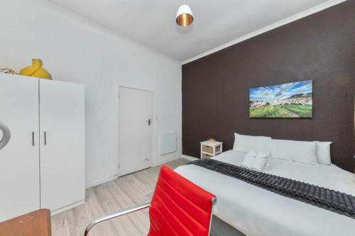 een slaapkamer met een groot wit bed en een rode stoel bij Modern and Stylish 2 BD House in Claremont in Kaapstad