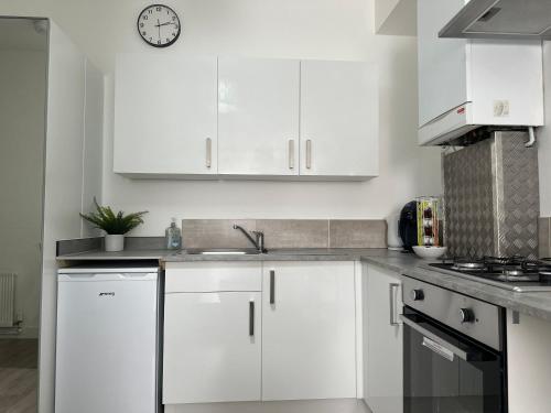 a kitchen with white cabinets and a clock on the wall at High Barnet Studio Flat in Barnet