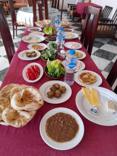 einen Tisch mit Teller mit Lebensmitteln auf einem roten Tischtuch in der Unterkunft Delmon Hotel in El-Tor