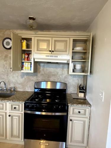 a kitchen with a black stove and white cabinets at Spacious 2nd floor Suite in Gloucester