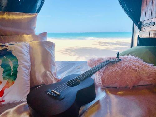 una guitarra sentada en una almohada junto a un osito de peluche en Camper Van Hawaii, en Kaneohe