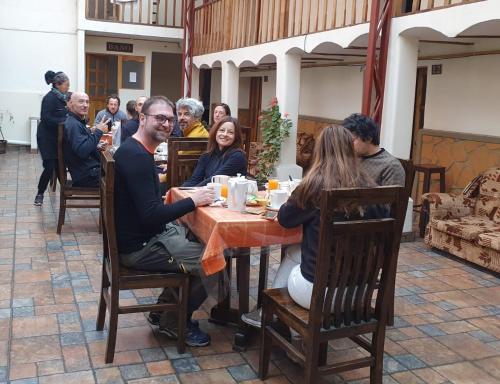 un grupo de personas sentadas alrededor de una mesa en Los Faroles Hostal, en Potosí