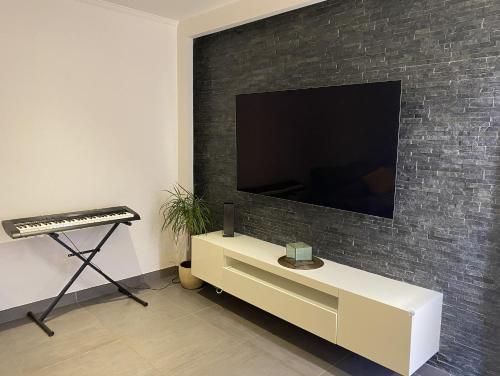 un soggiorno con una grande TV su un muro di mattoni di Maison Lyon-Bron Eurexpo - Stadium Groupama a Bron