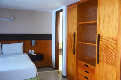 a bedroom with a bed and a wooden closet at Suítes Natal Plaza - Apto 1812 in Natal