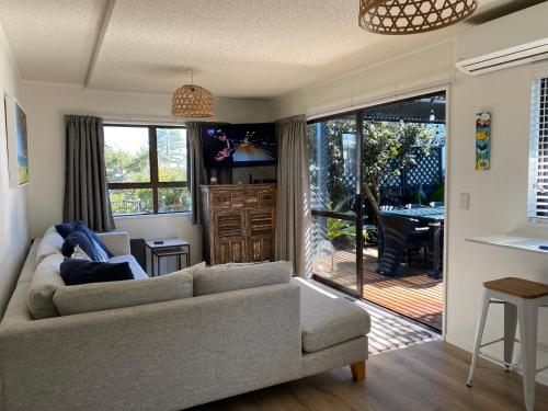 uma sala de estar com um sofá e uma porta de vidro deslizante em Vicroad The Mount em Mount Maunganui