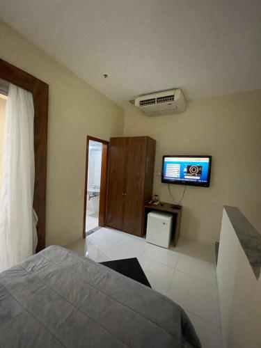 a bedroom with a bed and a tv on the wall at COBERTURA DUPLEX 70 m COM HIDRO NO MELHOR HOTEL DE TAGUATINGA in Taguatinga