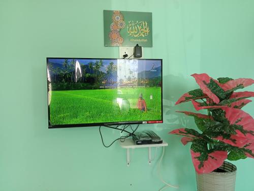 Minimalist Homestay D Pokok Sena في Pokok Sena: تلفزيون بشاشة مسطحة معلق على الحائط