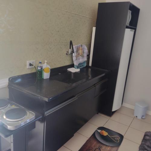 a bathroom with a black sink and a refrigerator at Kitnet próximo ao parque exposições in Maringá