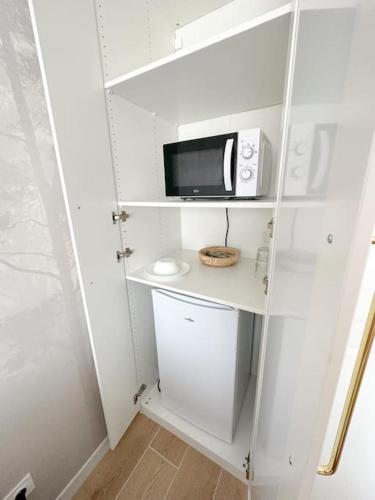 - une petite cuisine blanche avec un four micro-ondes et un comptoir dans l'établissement Studio indépendant, à Marigny-Saint-Marcel