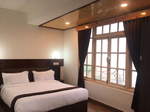 ein Schlafzimmer mit einem Bett und einem großen Fenster in der Unterkunft HOTEL ANGS RETREAT in Gangtok