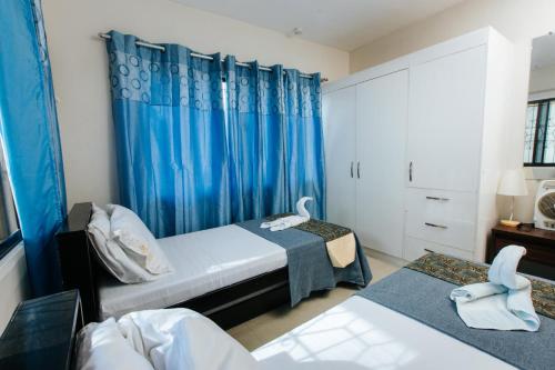 a bedroom with two beds and a blue curtain at Bahay Ni Kikay Vacation Rental - WiFi Included in General Santos
