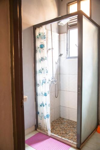 a shower with a glass door in a bathroom at Ruhuka House - connexion STARLINK privée & gratuite in Bujumbura
